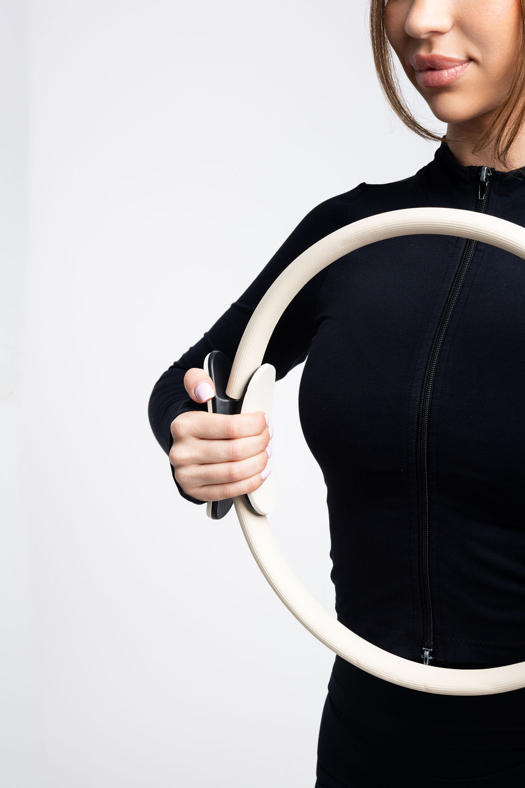 Woman in black holding the Pilates 101 ivory Pilates ring